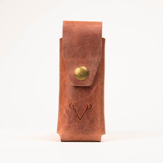 Full-grain leather multi-tool sheath showing grain and rivets